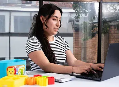 Persona frente a un portátil, con un juego de bloques sobre la mesa.